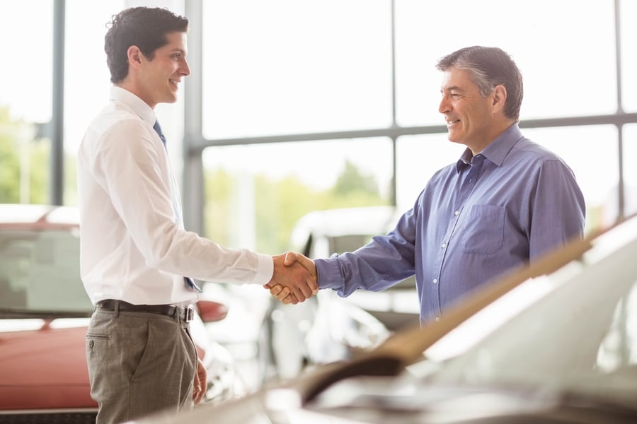 Businessman shaking a customer hand at new car showroom-1
